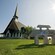 A chapel near trees, a lawn and a sign that reads Jardin Des Glaciers